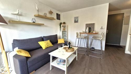 un salon avec un canapé bleu et une table dans l'établissement Royan - VERITABLE PERLE pour cet APPARTEMENT au charme apaisant - WIFI, à Royan