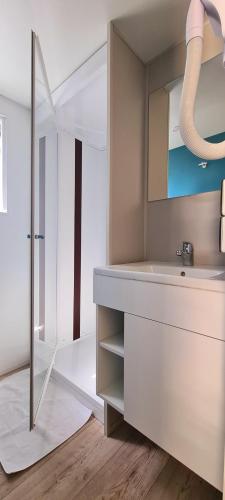 une salle de bain avec un lavabo et un miroir dans l'établissement Camping La Grand'Terre 4 étoiles - Linge de maison inclus - Clim - TV - Plancha - Lave-vaisselle - 4 personnes 2 chambres, à Ruoms