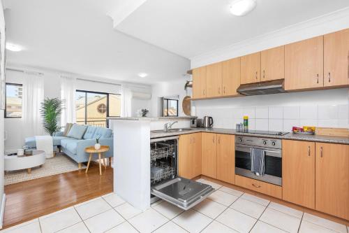 a kitchen with wooden cabinets and a living room at The Petal & Pod - A Sepal Stay in Perth