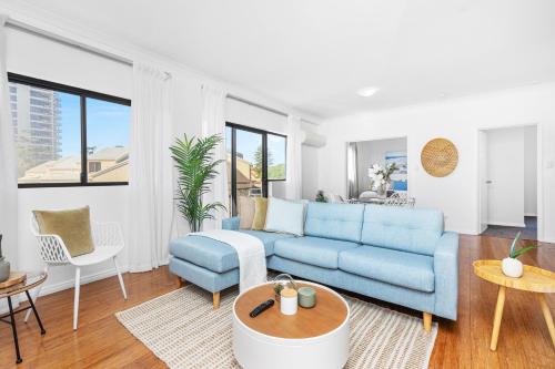 a living room with a blue couch and a table at The Petal & Pod - A Sepal Stay in Perth