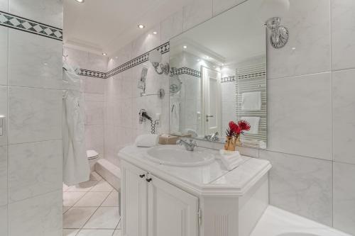 a white bathroom with a sink and a mirror at Strönhof Kampen in Kampen