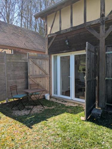 a house with a door and a table and a bench at La sellerie - small barn in Saint-Aubin-Epinay