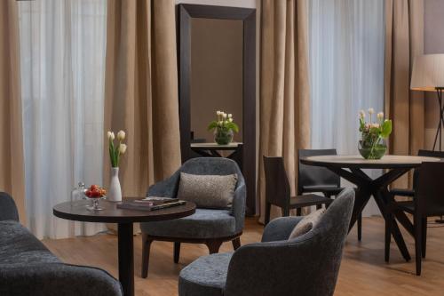 a living room with chairs and tables and a mirror at NH Collection Palermo Palazzo Sitano in Palermo