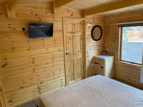 a log cabin bedroom with a tv on the wall at Lakeside Lodge 1, with Log burning Hot Tub in Everton