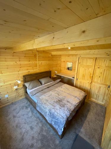 a bedroom with a bed in a wooden cabin at Lakeside Lodge 1, with Log burning Hot Tub in Everton
