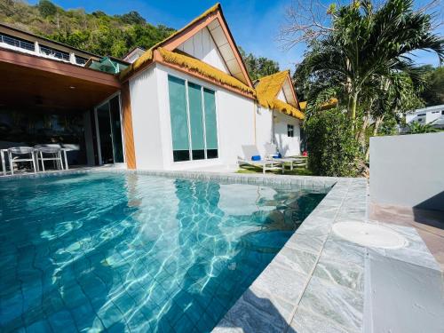 a swimming pool in front of a house at Baan Saint-Tropez Seaview Villas Kata Beach in Kata Beach
