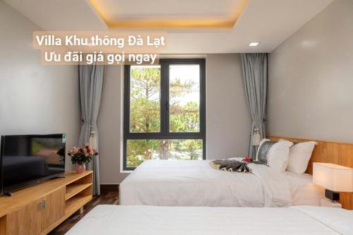 a bedroom with two beds and a tv and a window at Chillin Villa - Biệt Thự Đà Lạt Khu Nhiều Thông Gần Hồ Tuyền Lâm in Xuan An