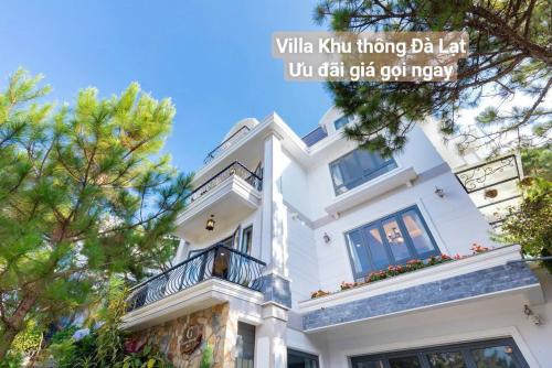 a white house with a balcony and trees at Chillin Villa - Biệt Thự Đà Lạt Khu Nhiều Thông Gần Hồ Tuyền Lâm in Xuan An