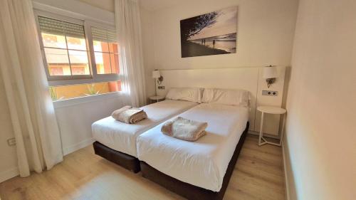 a bedroom with a white bed with two pillows on it at Apartamento moderno en un Resort de 4 Estrellas in Islantilla