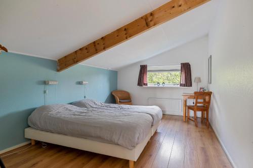 a bedroom with a bed and a desk and a window at Huis Specht is perfect voor vakantie nabij meer en tuin op zuiden in Grou