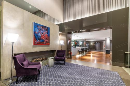 a lobby with two chairs and a painting on the wall at InterContinental São Paulo by IHG in Sao Paulo