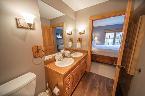 ein Bad mit zwei Waschbecken und einem Bett in der Unterkunft Expedition Station 8593 by SummitCove Lodging in Keystone