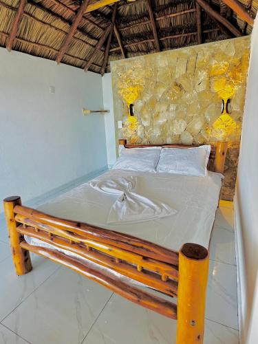 a bed in a room with a stone wall at Bush Beach Backpackers in Vilanculos