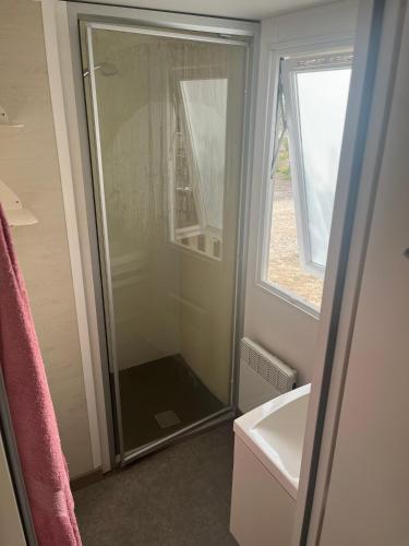 La salle de bains est pourvue d'une douche en verre et d'une fenêtre. dans l'établissement Camping 5étoiles, Torreilles Plage, à Torreilles