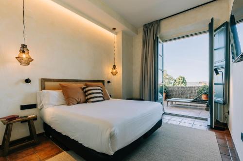 a bedroom with a bed and a sliding glass door at Gran Claustre Boutique Hotel in Altafulla