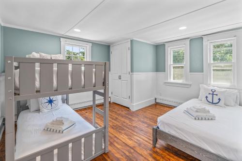 a bedroom with two bunk beds and two windows at The White Pillars in South Dennis