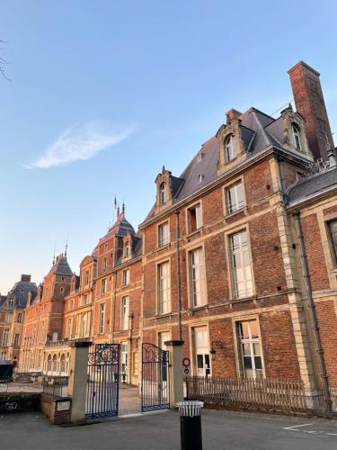 a large red brick building with a black fence at La Montpensier - maison dans le centre ville d'Eu in Eu