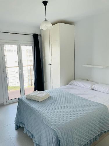 a white bedroom with a large white bed and a window at Apartamento playa in Blanes