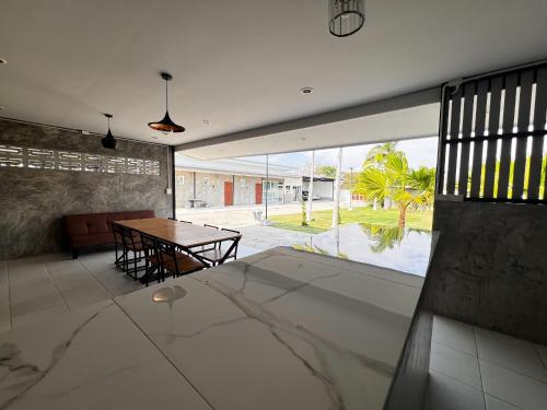 a living room with a table and a glass wall at Baan Bua Homestay & Poolvilla in Ban Pa Mak (1)