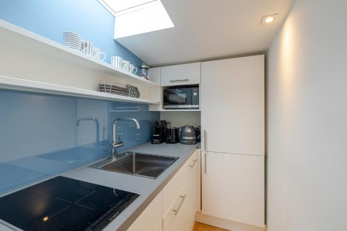 a kitchen with white cabinets and a sink at Strönhof Kampen in Kampen