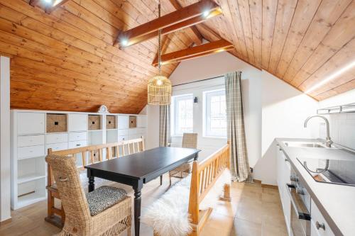 a kitchen with a black table and chairs and a wooden ceiling at Hotel Hvezda in Pec pod Sněžkou