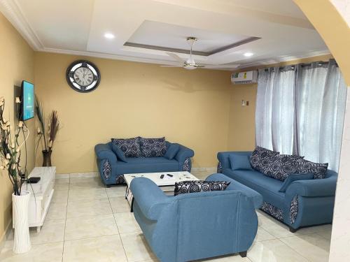 a living room with two blue couches and a clock at Sokea Safari Lodge And Suites in Kasoa
