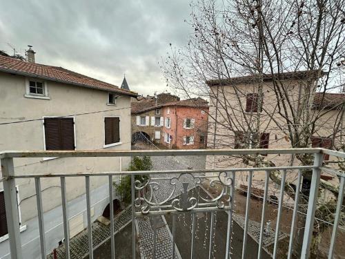 - un balcon avec une clôture et des bâtiments dans l'établissement Charmant avec petit balcon au coeur du village, à Thurins