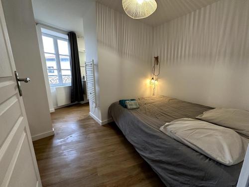 - une chambre avec un grand lit dans une pièce dotée d'une fenêtre dans l'établissement Charmant avec petit balcon au coeur du village, à Thurins