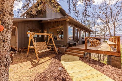 a house with a deck with chairs and a tree at SMOKY MOUNTAIN MAGIC-Spectacular Views, 3 Br, Sleeps 8, Hot Tub in Bryson City