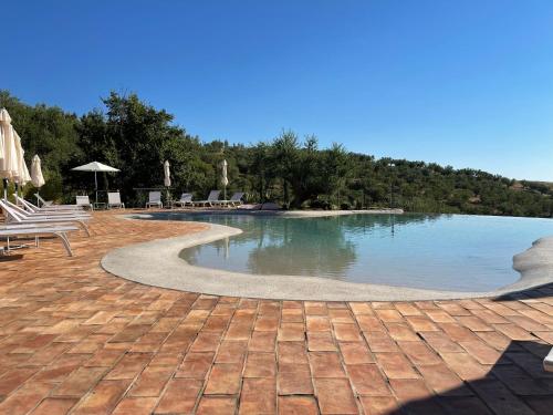a swimming pool with chairs and umbrellas next to at Castello di Serragiumenta in Firmo