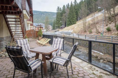 a table and chairs on a balcony with a view of a river at Hotel Hvezda in Pec pod Sněžkou