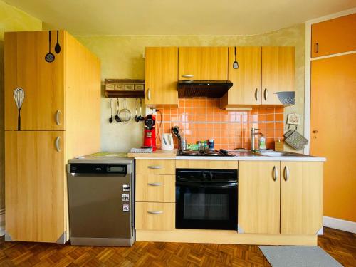 - une cuisine avec des placards en bois et un lave-vaisselle noir dans l'établissement Parenthèse de Calme - 380, à Rouen