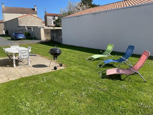 - un groupe de chaises et un grill dans la cour dans l'établissement Coeur bocage Vendéen 16 Km du Puy du Fou, à Les Landes-Génusson