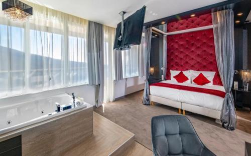 a bedroom with a bed with a red headboard and a tub at Hotel Ózon & Luxury Villas in Mátraháza