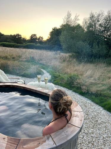 a woman sitting in a hot tub with wine glasses at Humphrey Hut in Southborough