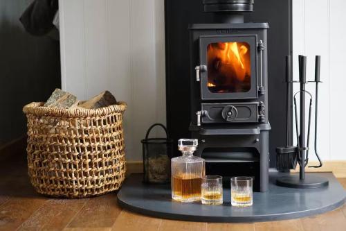 a living room with a stove with two glasses and a basket at Humphrey Hut in Southborough