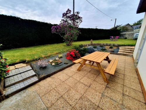 a patio with a picnic table and a pond at L'abri in Trémuson