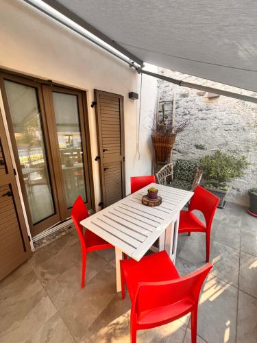 a white table and red chairs on a patio at Stanza in sondrio Coel in Sondrio