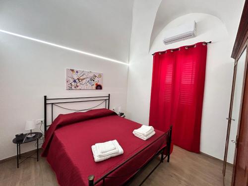 a bedroom with a red bed and red curtains at Appartamento Il Dammuso in Marsala