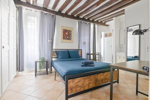 - une chambre avec un lit avec des draps bleus et une table dans l'établissement Heart of Paris - 1BR - 4P - Le Marais 7 Free Netflix, à Paris