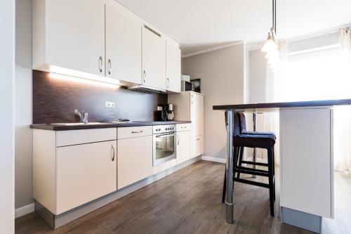 a kitchen with white cabinets and a black counter top at Fehmarnstrand 78 App 12 in Staberdorf