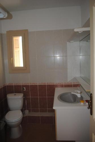 une salle de bain avec toilettes, lavabo et fenêtre dans l'établissement Gîte Les 2 oliviers, à Canet