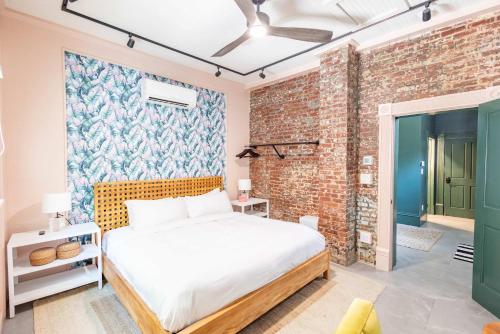 キーウェストにあるGreen Room at the Grand Maloneyのベッドとレンガの壁がある寝室