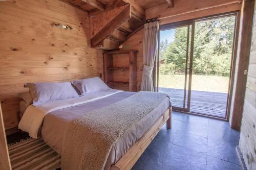 a bed in a wooden room with a large window at Cabaña en Pucon in Pucón
