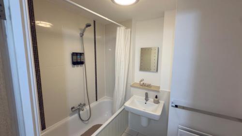 a white bathroom with a sink and a shower at Central M K 2-Bedroom Apartment Sleeps 4 Parking in Milton Keynes