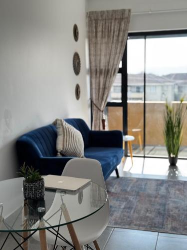 a living room with a blue couch and a glass table at Sheffield Hills in Ballito