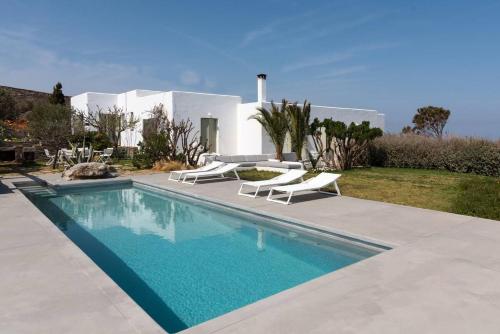 a swimming pool with two lounge chairs and a house at Villa Kea in Kastrianí