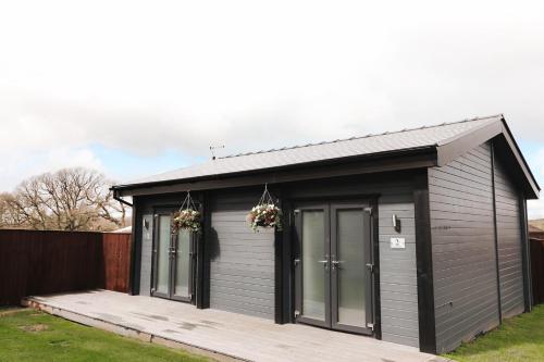 a small grey shed with two doors and a porch at Oldwalls Gower in Llanrhidian