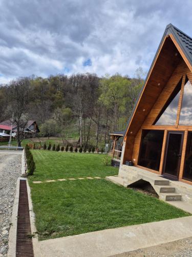 a house with a grassy yard next to a building at Cabana AFrame Olanesti in Băile Olăneşti
