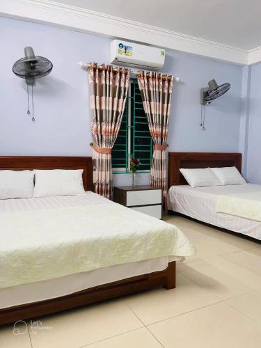 a bedroom with two beds and a window at Nhà nghỉ Thường Nga in Cat Ba
